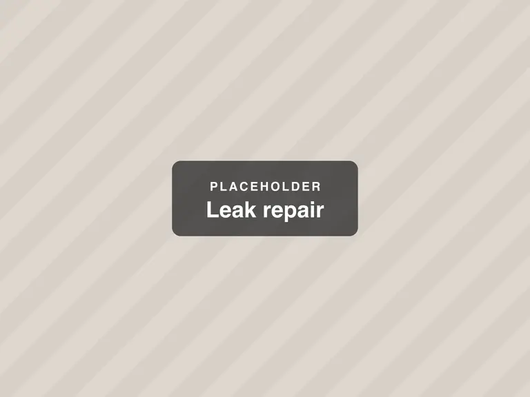 A plumber fixing a leaking pipe under a sink